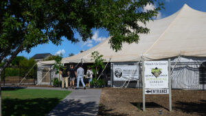 Pecan Lakes Entertainment venue featuring a large Farmer's Market tent with four individuals walking inside the tent.