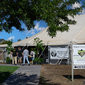 Pecan Lakes Entertainment venue featuring a large Farmer's Market tent with four individuals walking inside the tent.